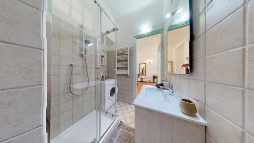 une salle de bain avec une douche, un lavabo et un miroir dans l'établissement Les Fleurs Astoria, à Menton