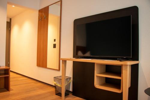 a flat screen tv on a stand in a room at AMANTE Hotel - Bern Airport in Belp