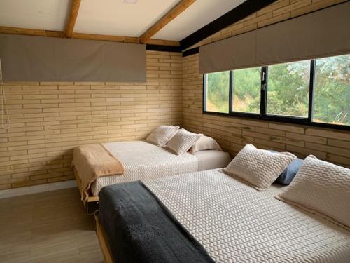 two beds in a room with two windows at Casa de Campo Xiua Laguna d Fúquene in Fúquene