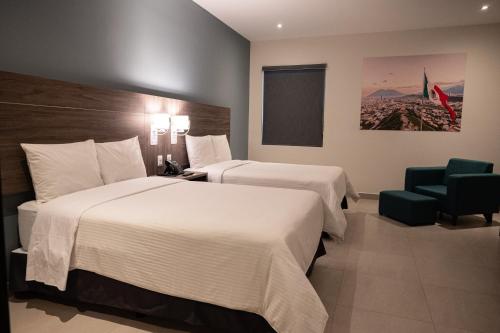 a hotel room with two beds and a chair at Hotel Centria in Monterrey