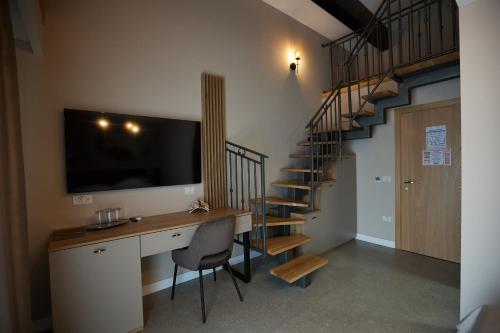 a room with a desk with a television and a staircase at Pensiune Restaurant Pizzerie 2 Păuni in Borşa