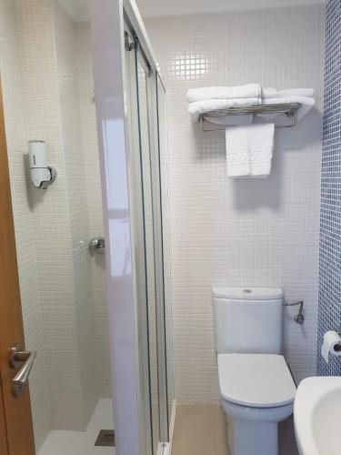 a bathroom with a toilet and a shower with towels at A Torre in Sarria