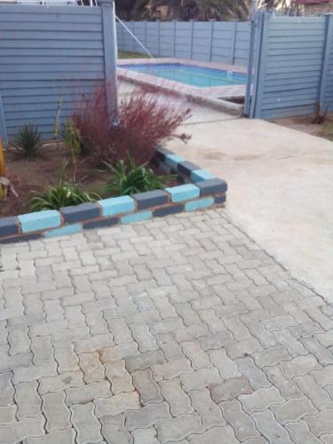 a brick walkway with a fence and a pool at PS GOOD TIME GUEST HOUSE Contractor Group Accommodation Klerksdorp in Klerksdorp