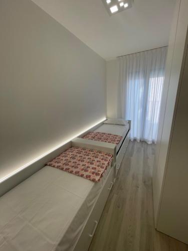 two beds in a small room with a window at Haus Margarete - Agenzia Cocal in Caorle