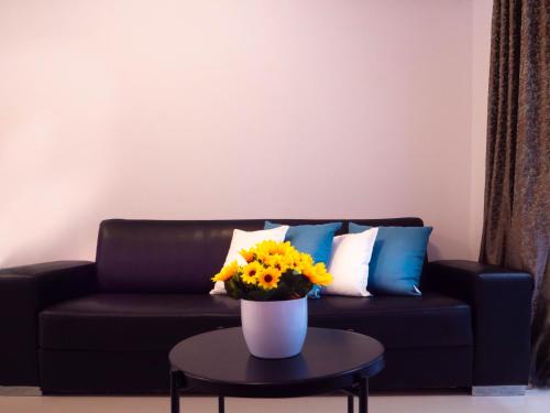 a black couch with a vase of flowers on a table at CityScape Gzira Holiday Apartments and Penthouse in Il-Gżira