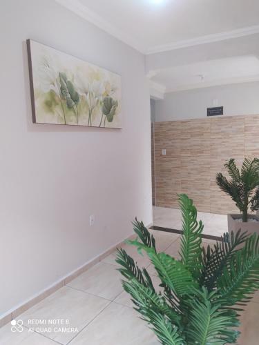 um lobby com uma pintura na parede e plantas em Pousada Quarto com tv,ar,frigobar,wifi e garagem em Aparecida