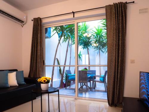 ein Wohnzimmer mit einem Sofa und einem Balkon mit Palmen in der Unterkunft CityScape Gzira Holiday Apartments and Penthouses By ShortletsMalta in Gżira