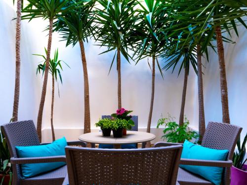 a patio with palm trees and a table and chairs at CityScape Gzira Holiday Apartments and Penthouse in Il-Gżira