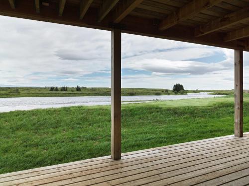 a porch with a view of a field and a river at Laxá Lodge in Hella