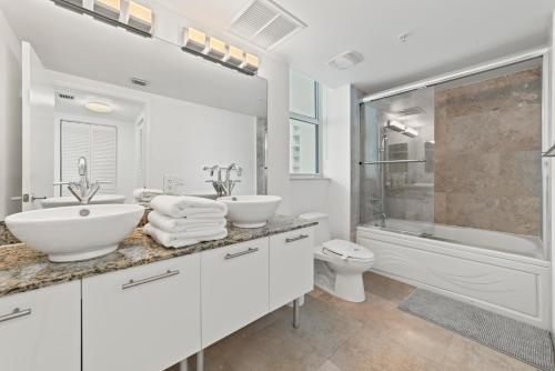 a white bathroom with two sinks and a shower at Skyline Serenity - Brickell On The River 1901 - Bi-Level Loft with Breathtaking Views On The Ocean in Miami