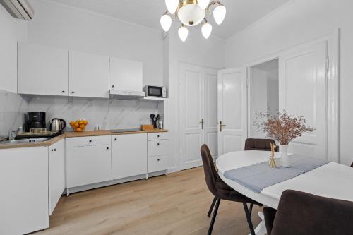 een keuken met witte kasten en een tafel met stoelen bij White Imperial Apartment in Pula