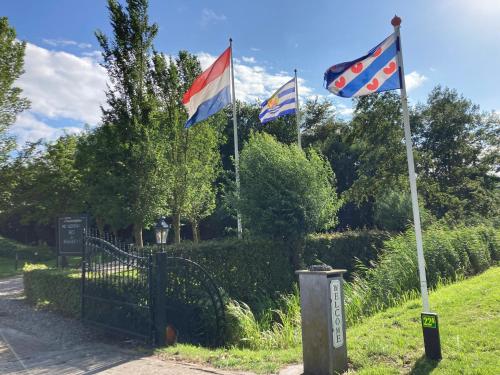 two flags on a pole next to a fence at B&B Stations Koffiehuis in Molkwerum