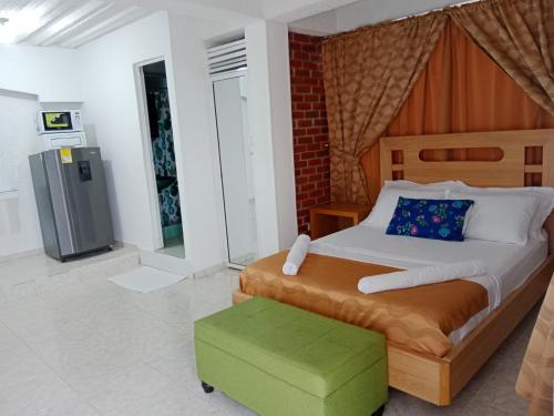 a bedroom with a large bed and a green ottoman at HOTEL SAN MARINO TUMACO in Tumaco