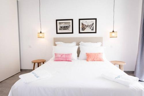 sypialnia z białym łóżkiem i różowymi poduszkami w obiekcie TI PUNCH, appartement 3 pièces neuf, front de mer w mieście Les Anses-d'Arlet