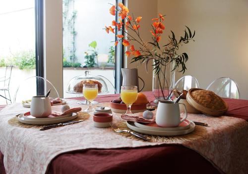 une table avec un tissu de table et des verres de jus d'orange dans l'établissement Maison d'Hôtes " L'INSTANT D'AILLEURS", à Albi