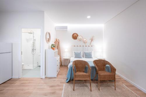 a white bedroom with a bed and two chairs at Quinta Das Essências in Penafiel