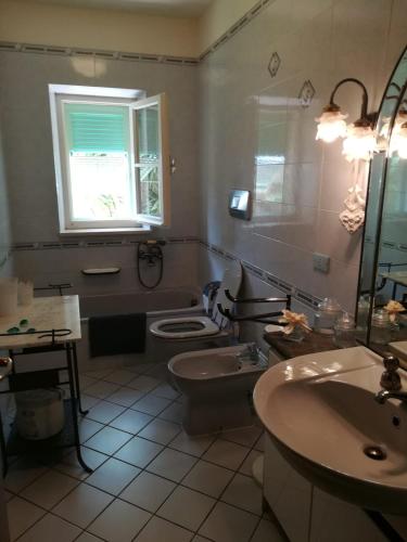 a bathroom with a toilet and a sink and a window at Villa Adriana in Capoliveri