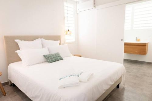a white bed with two towels on top of it at Ti soleil, appartement 3 pièces neuf, front de mer in Les Anses-dʼArlets