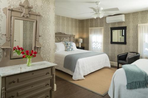 a bedroom with a bed and a dresser with a mirror at The Carroll Villa Hotel in Cape May