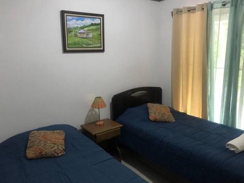 マヌエル・アントニオにあるApto Cielo Azul No7のベッドルーム1室(ベッド2台、ランプ付きテーブル付)