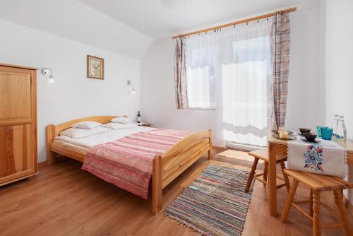 a bedroom with a bed and a table and a window at Dom Wypoczynkowy IRMINA in Karwia