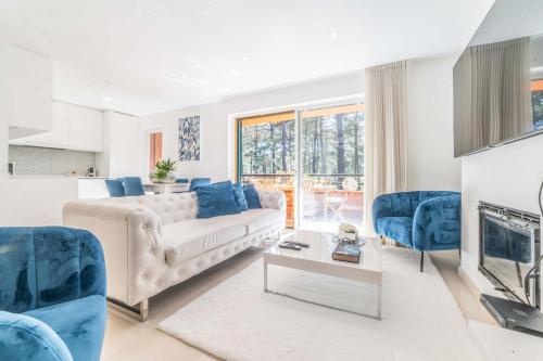 uma sala de estar com um sofá branco e cadeiras azuis em Apartment Aroeira Green Jodi em Aroeira