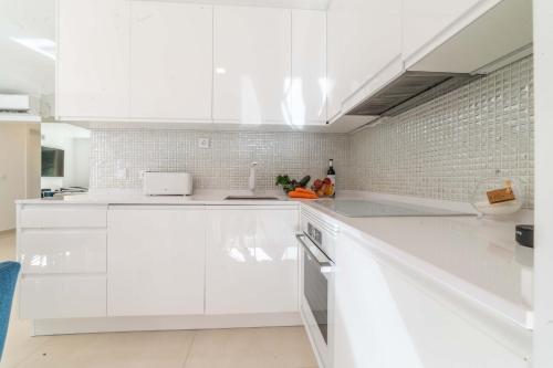 cocina blanca con armarios blancos y pared de ladrillo en Apartment Aroeira Green Jodi, en Aroeira