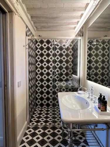 a bathroom with a sink and a black and white tiled shower at Casa del Fauno in Montepulciano