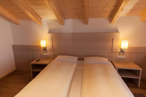 2 Betten in einem Zimmer mit 2 Tischen und 2 Lampen in der Unterkunft Residence Armonia in Kolfuschg