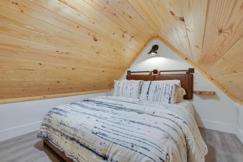 Ce lit se trouve dans un dortoir doté d'un plafond en bois. dans l'établissement 16 Bluebird Feather Tiny Cottage, à Scottsboro