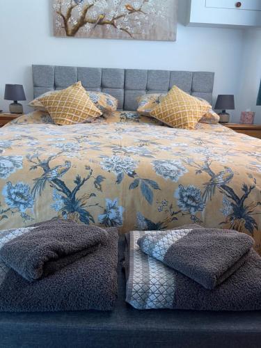 a bedroom with a bed with a floral bedspread and pillows at Chestnut Cottage in East Bergholt