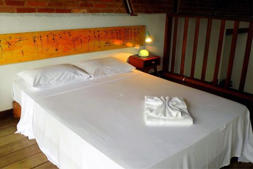 a bedroom with a white bed with a wooden headboard at Atobá Villas in Paraty