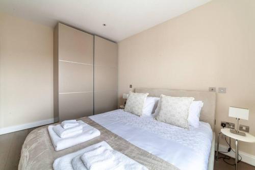 um quarto branco com uma cama com toalhas em Spacious Modern One Bedroom Flat in Chelsea em Londres