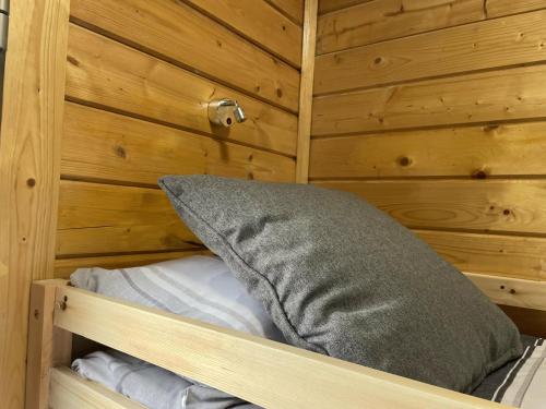 Cama con almohada en habitación de madera en Immaculate cabin 5 mins to Inverness dogs welcome en Inverness