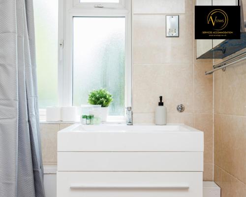 een badkamer met een witte wastafel en een raam bij Large 2 Bed Apartment by AV Stays East Croydon in South Norwood