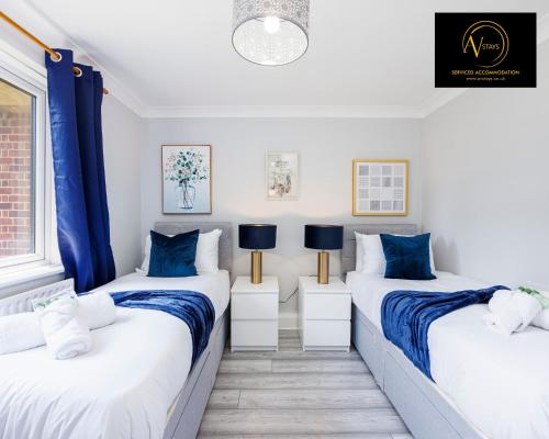 twee bedden in een kleine kamer met blauwe gordijnen bij Large 2 Bed Apartment by AV Stays East Croydon in South Norwood
