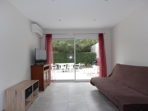 Il comprend un salon avec un canapé et une télévision. dans l'établissement Les logis de Magali Les Acacias, maison, clim, parking, à Argelès-sur-Mer