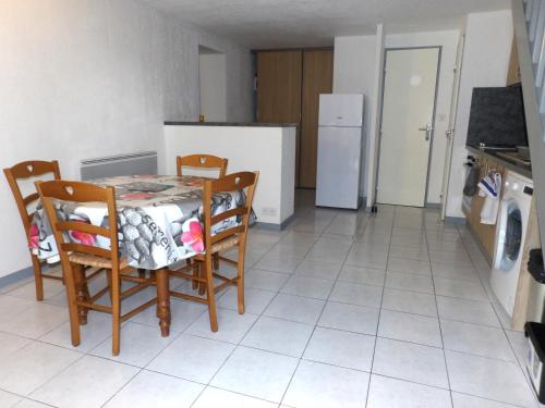 une cuisine avec une table, des chaises et un réfrigérateur dans l'établissement Les logis de Magali Les Acacias, maison, clim, parking, à Argelès-sur-Mer