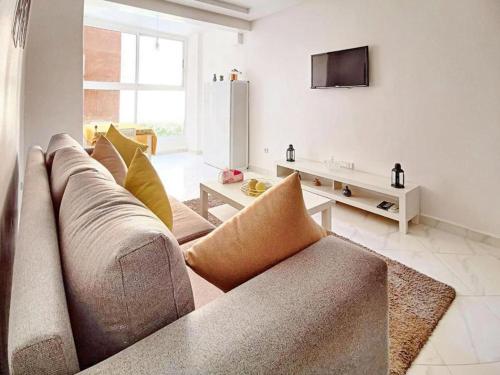 sala de estar con sofá y TV en appartement center de Guéliz avec piscine, en Marrakech
