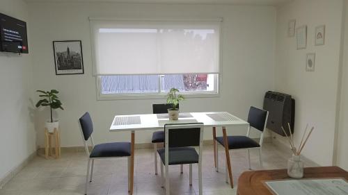 una mesa y sillas blancas en una habitación con ventana en Depto Albarracin en San Carlos de Bariloche