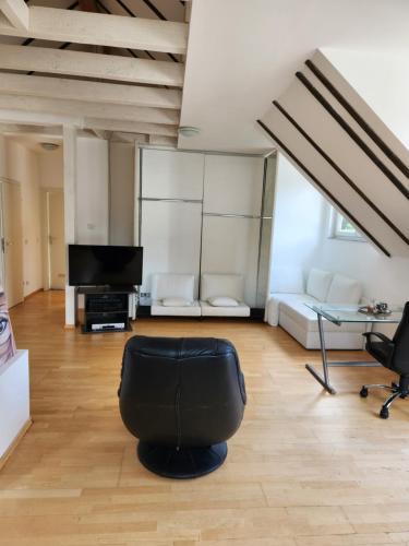 ein Wohnzimmer mit einem schwarzen Stuhl und einem TV in der Unterkunft Penthouse posh in Troisdorf