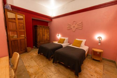 two beds in a room with red walls at Viajero Oaxaca Hostel in Oaxaca City