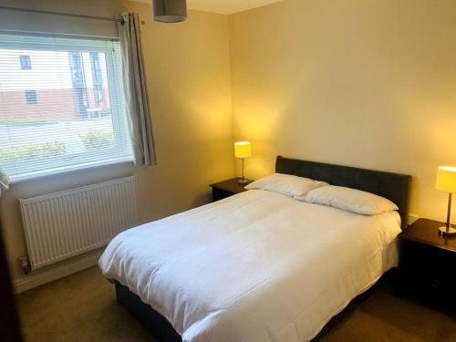 a bedroom with a large white bed with two lamps at Spacious Ground Floor Flat in Buckinghamshire