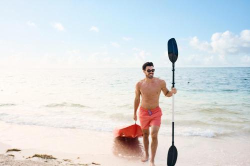 a man is walking on the beach with an oar at Chablé Maroma in Playa del Carmen