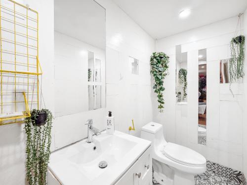 La salle de bains blanche est pourvue de toilettes et d'un lavabo. dans l'établissement BeHome by LuxUrban, à New York