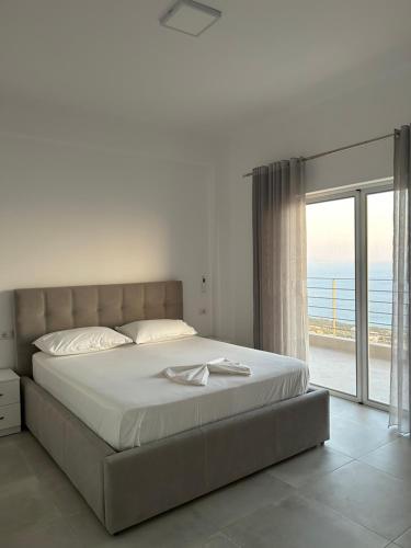 a bedroom with a large bed with a view of the ocean at Vila Jona Palasë in Dhërmi