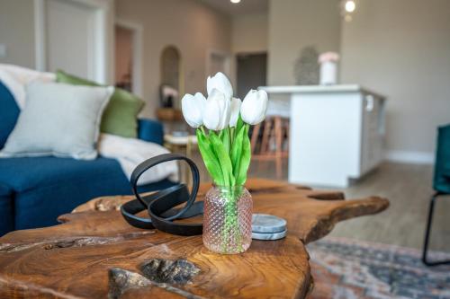 a vase with white flowers on a wooden table at Brand New and Very Spacious 1 Bedroom Condo! in Chatham