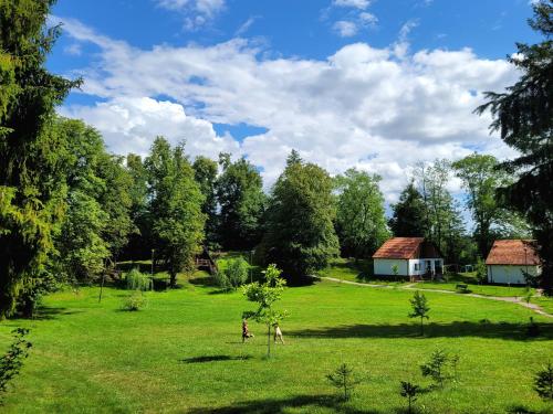 two people walking in a field with a house at Folwark Wierzchy in Wierzchy