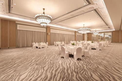 a banquet hall with white tables and chairs and chandeliers at Sheraton Abu Dhabi Hotel & Resort in Abu Dhabi