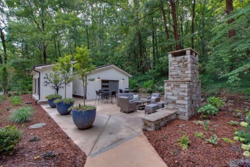 a patio with a stone fireplace and a table and chairs at Oak Luxury Treehouse near Lake Guntersville in Scottsboro